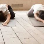 verlichting-darmklachten-met-yoga-vrouw-in-kindhouding-op-yogamat